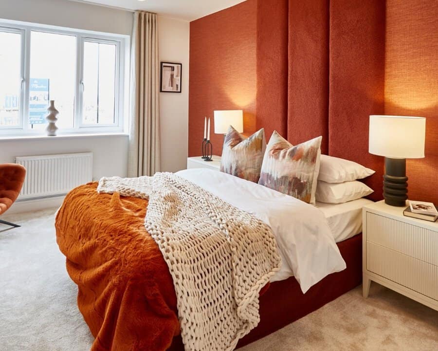 Luxurious bedroom with a burnt orange accent wall, cozy bedding, soft lighting, and modern decor.