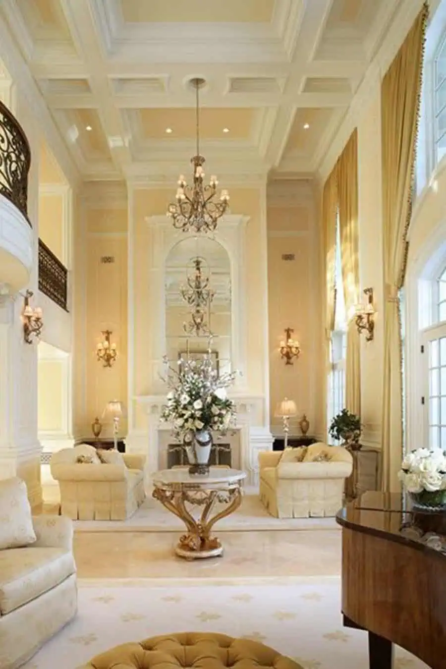 Luxury living room with a modern coffered ceiling, chandeliers, elegant furnishings, and tall windows.