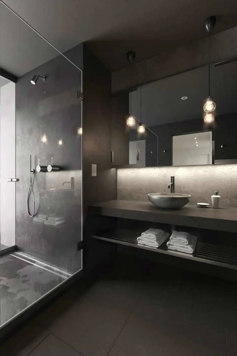 Luxury black bathroom with a glass shower, concrete vanity, and modern pendant lighting.