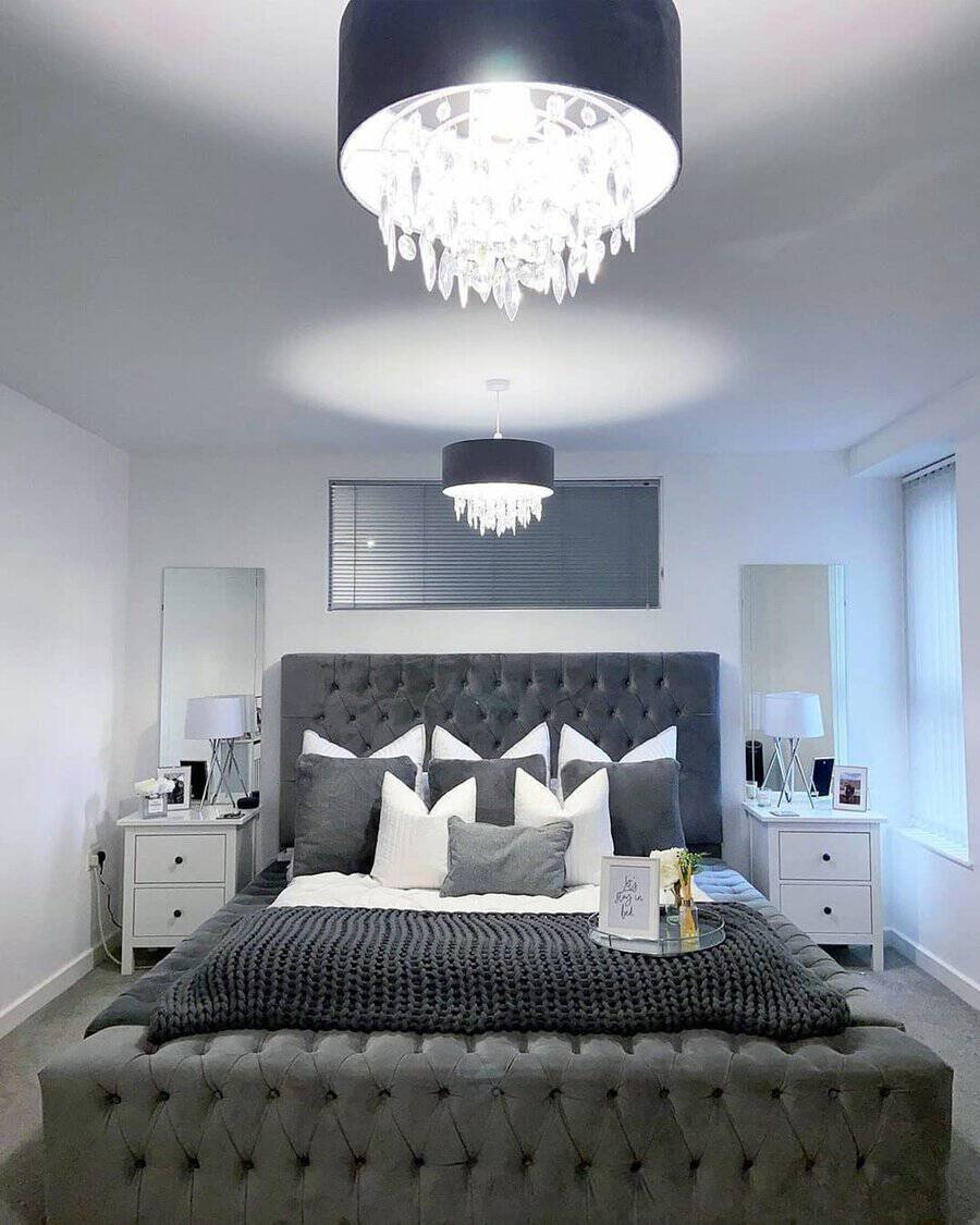 Luxury grey and white bedroom with a tufted bed, crystal chandeliers, and elegant decor.