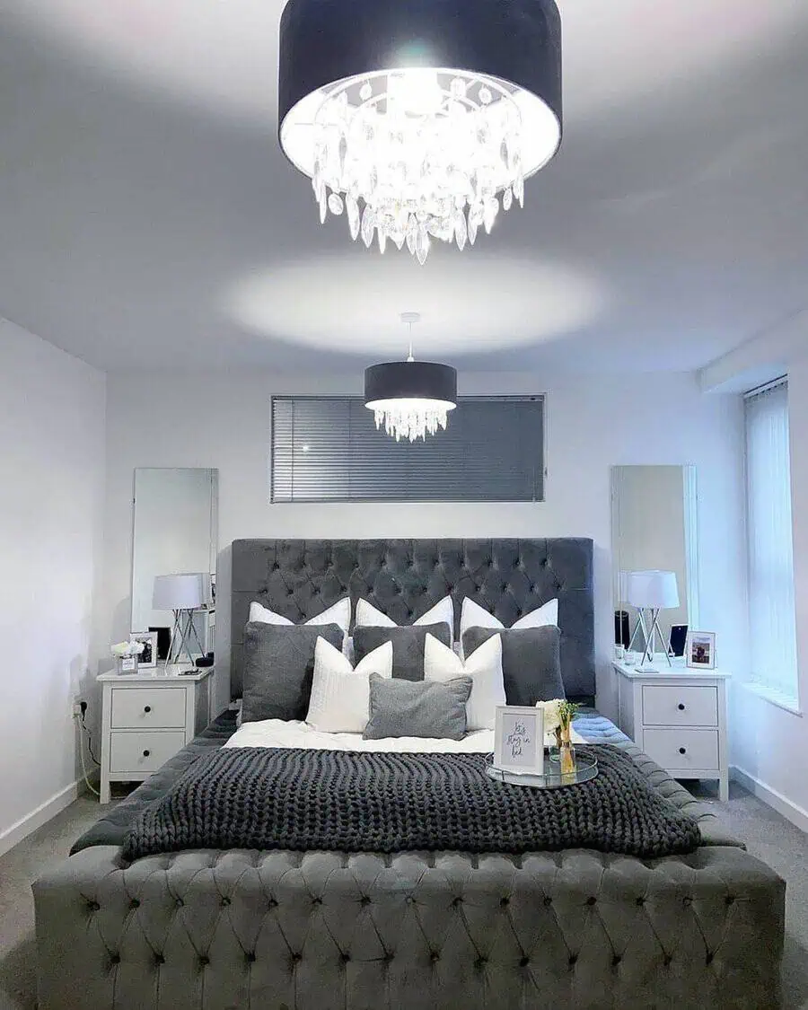 Luxury grey and white bedroom with a tufted bed, crystal chandeliers, and elegant decor.