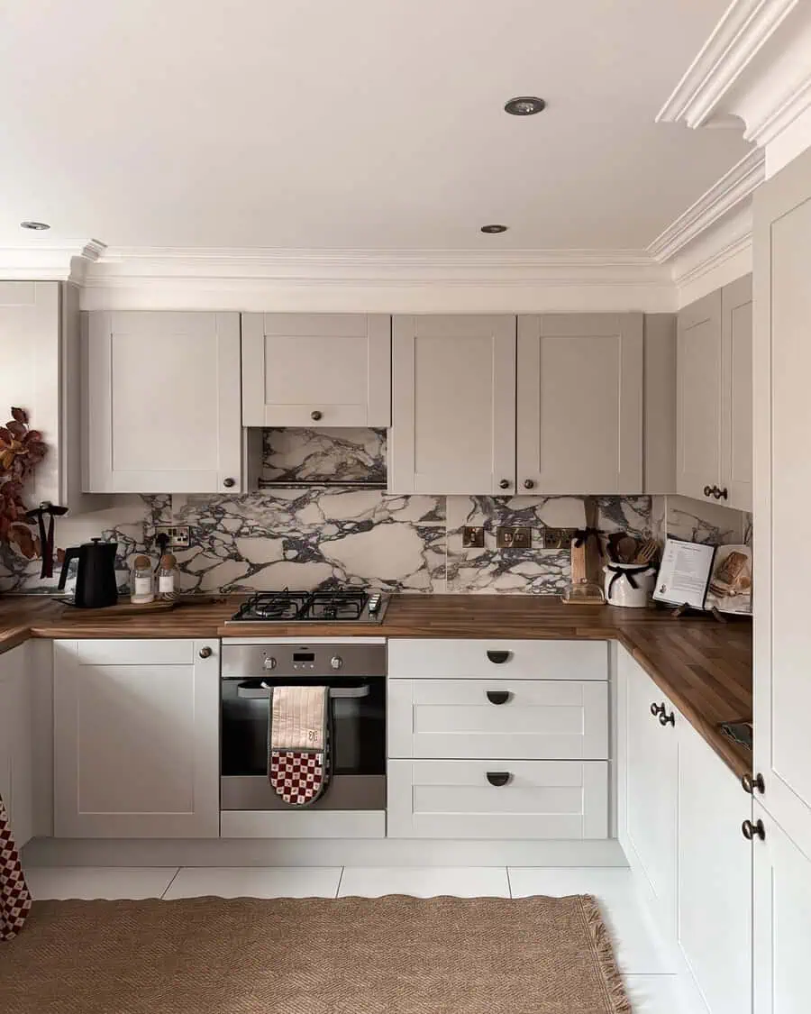 Marble backsplash with bold veining contrasts with white cabinets and wood countertops for a modern look.