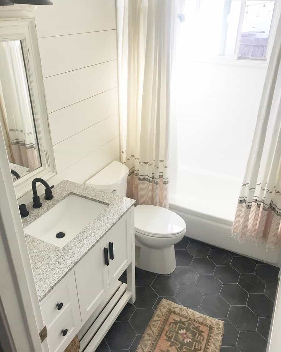 Black and white bathroom with matte black faucets, hexagon floor tiles, and a farmhouse vanity.