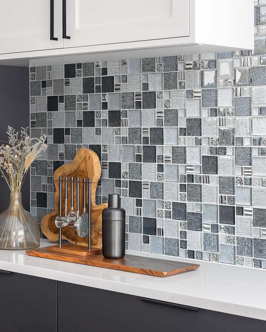 Metallic mosaic tile backsplash adds a sleek, modern touch to white cabinets and dark lower cabinetry.