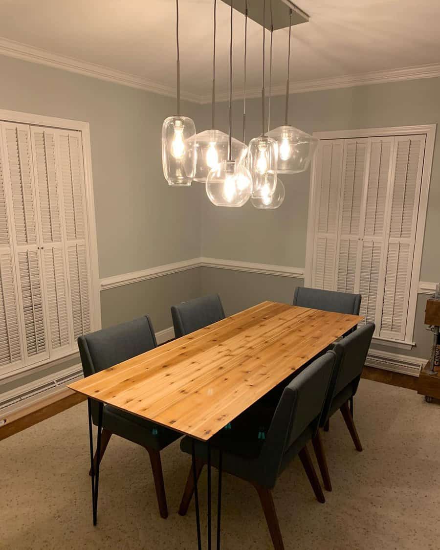 Mid-century Colonial house dining room with a wooden table, glass pendant lights, and blue chairs.