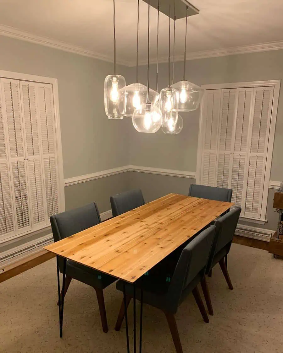 Mid-century Colonial house dining room with a wooden table, glass pendant lights, and blue chairs.