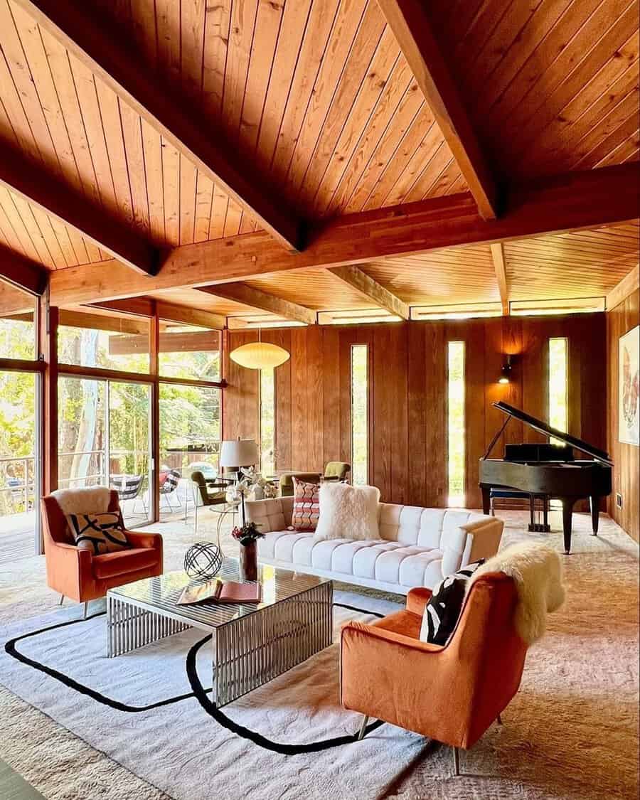 Mid-century modern living room with a wooden vaulted ceiling, orange chairs, and a grand piano.