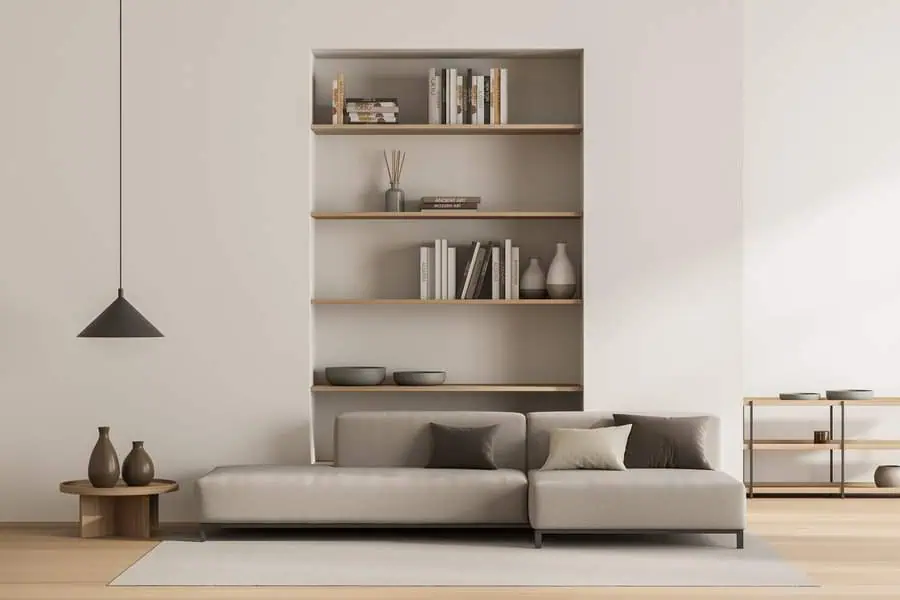 Minimalist living room with neutral sofa, built-in bookshelf, and modern decor accents.