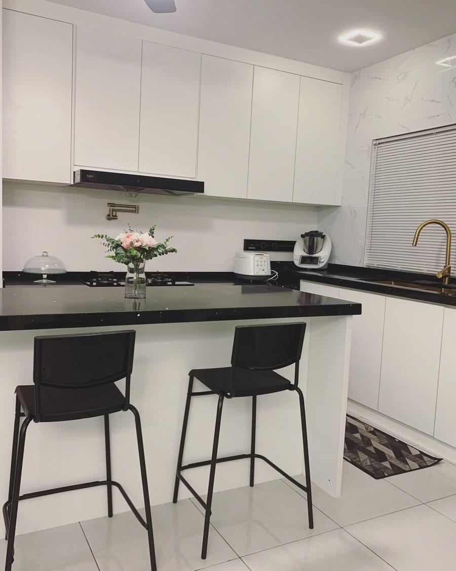 Minimalist modern kitchen with white cabinetry, black countertops, and sleek bar seating.