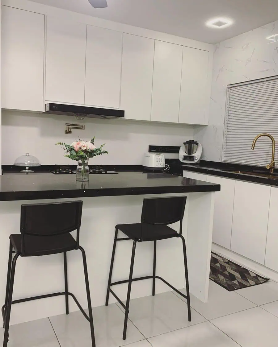 Minimalist modern kitchen with white cabinetry, black countertops, and sleek bar seating.