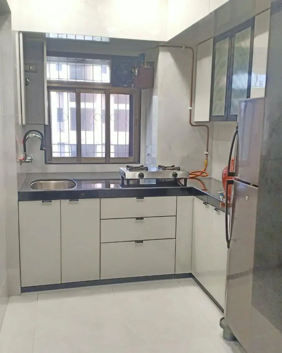 Minimalist modern kitchen with glossy white cabinets, black countertops, and a compact functional layout.