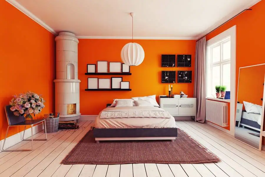 Modern bedroom with vibrant orange walls, minimalist furniture, a cozy bed, and stylish decor.