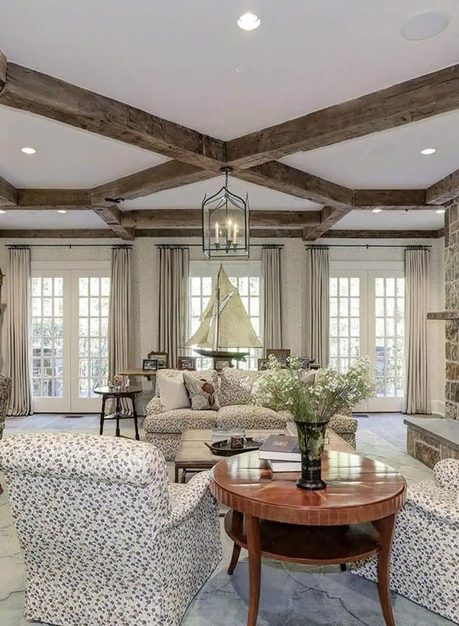 Rustic living room with a modern coffered ceiling, exposed wood beams, and floral-patterned seating.