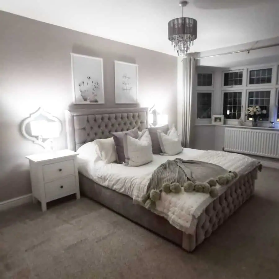 Cozy grey and white bedroom with a tufted bed, soft lighting, and elegant decor.