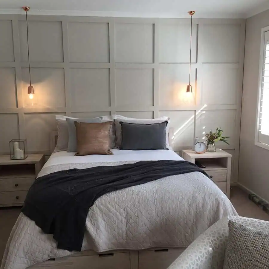 Modern bedroom with paneled accent wall, pendant lights, and neutral-toned bedding.