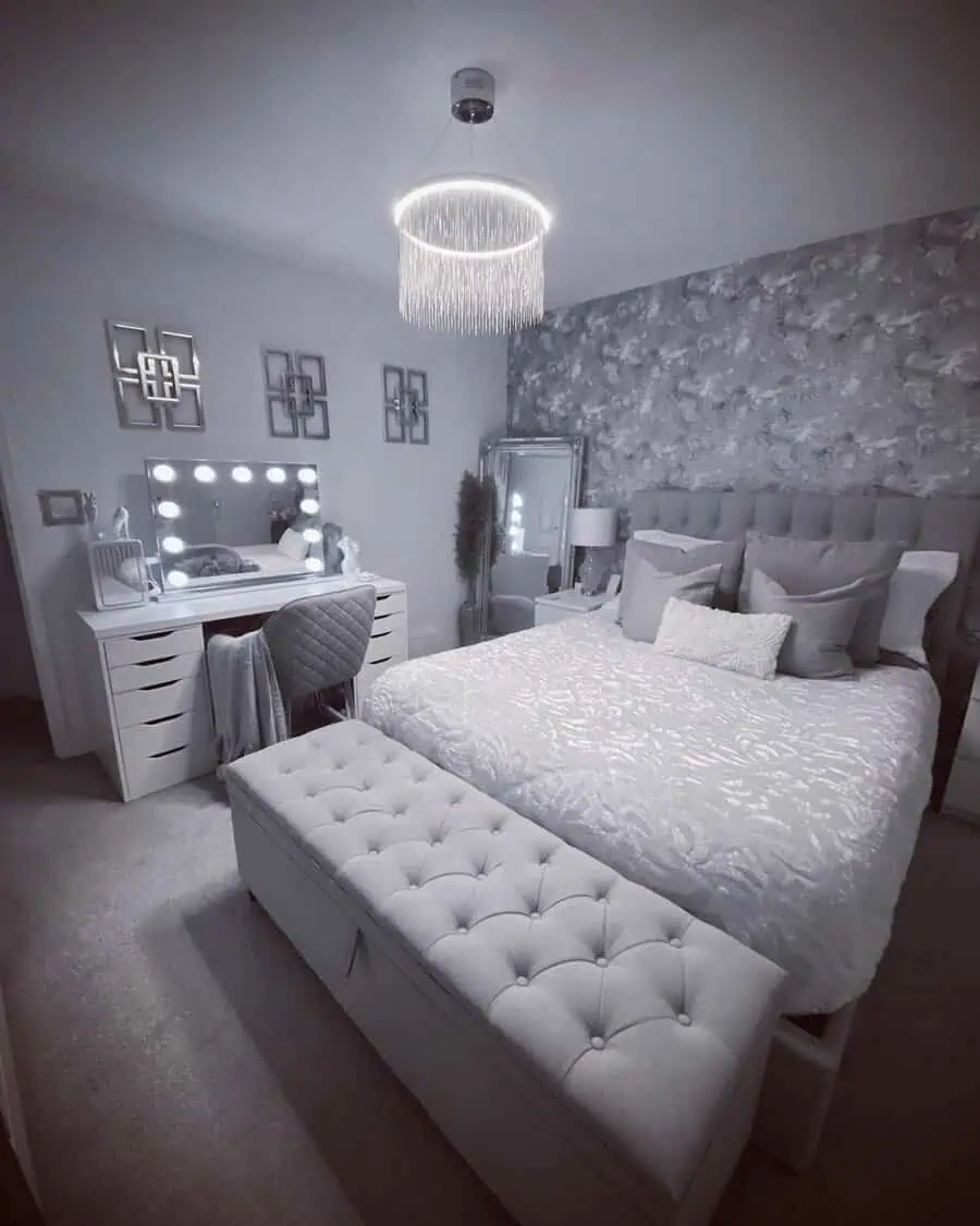 Chic grey and white bedroom with a tufted bed, vanity mirror, and statement chandelier.