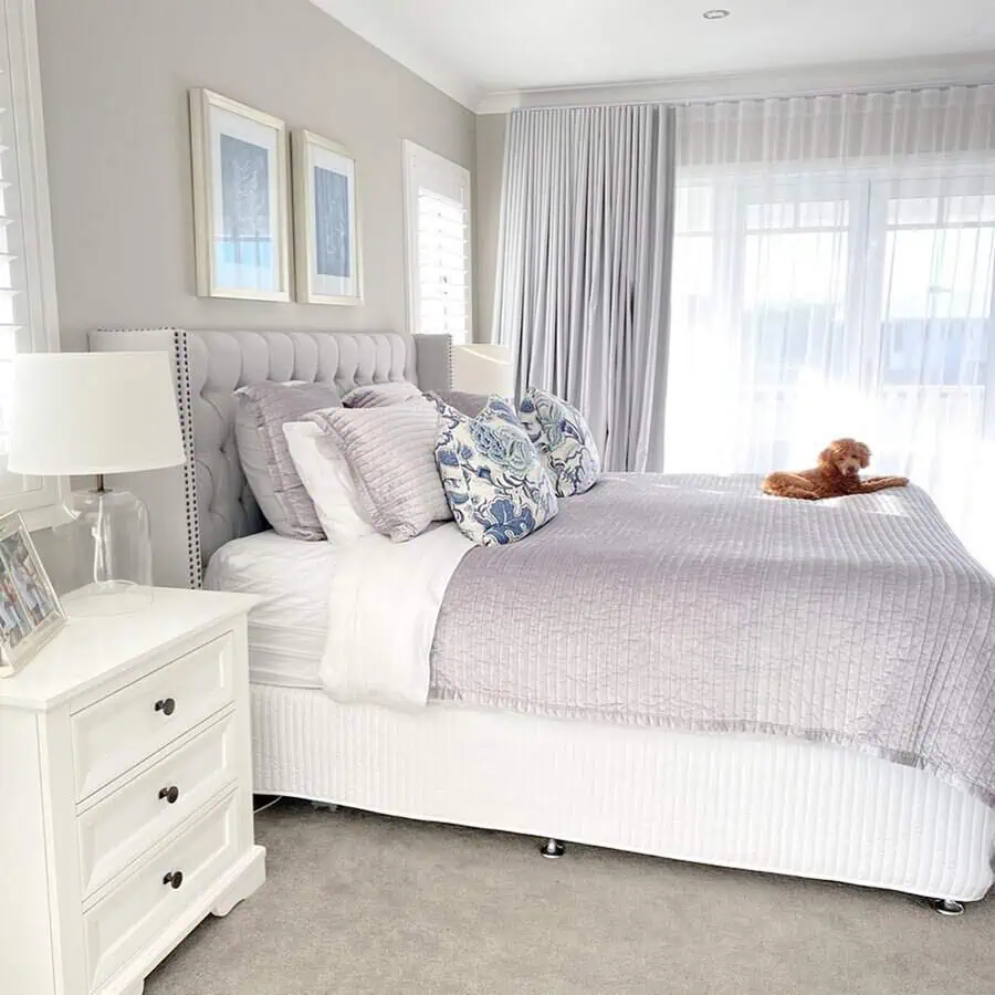 Bright grey and white bedroom with a tufted headboard, elegant decor, and sheer curtains.