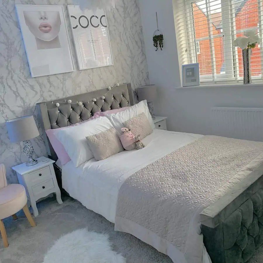 Modern grey and white bedroom with a tufted bed, marble accent wall, and stylish wall art.