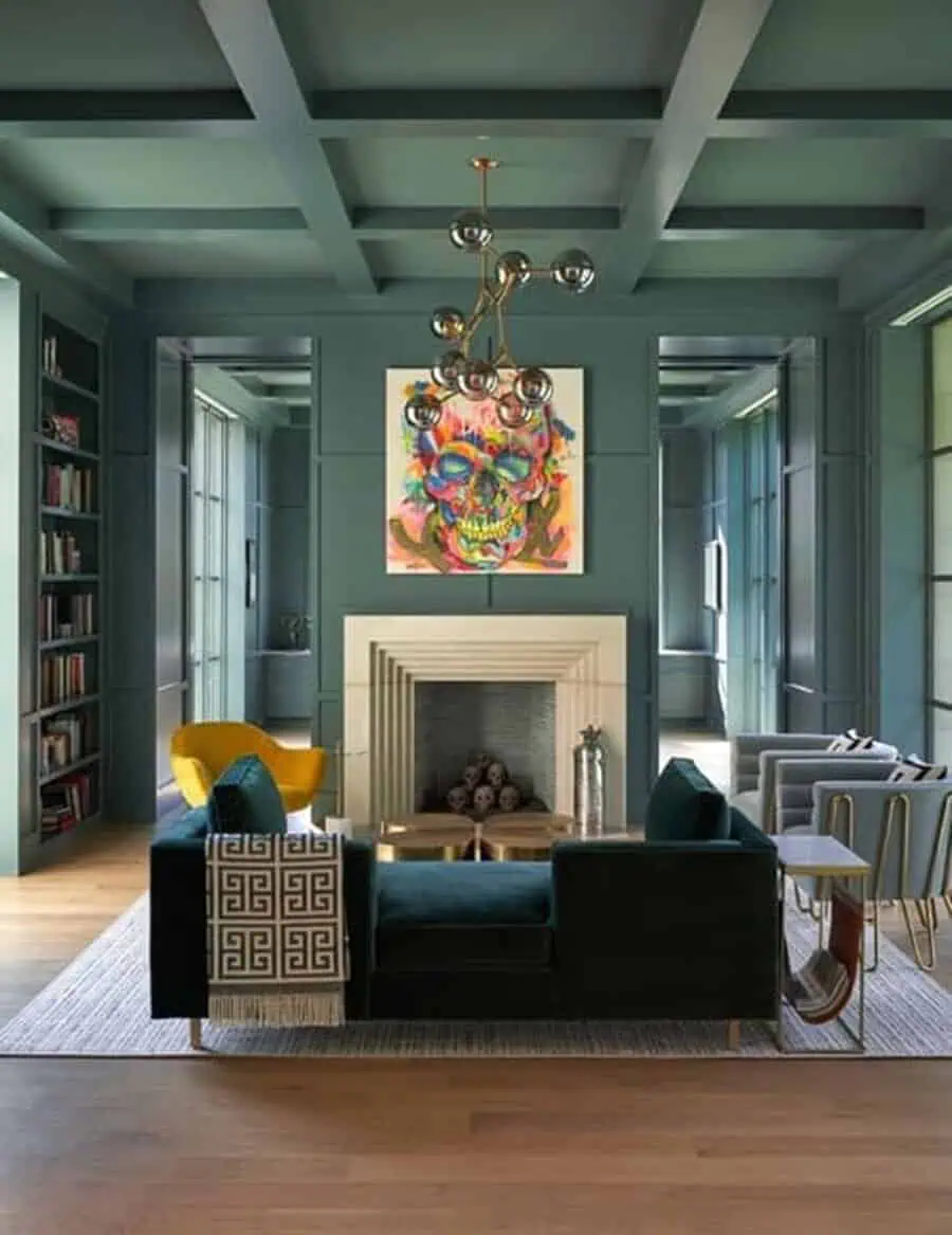 Modern living room with a bold coffered ceiling, statement chandelier, fireplace, and vibrant artwork.