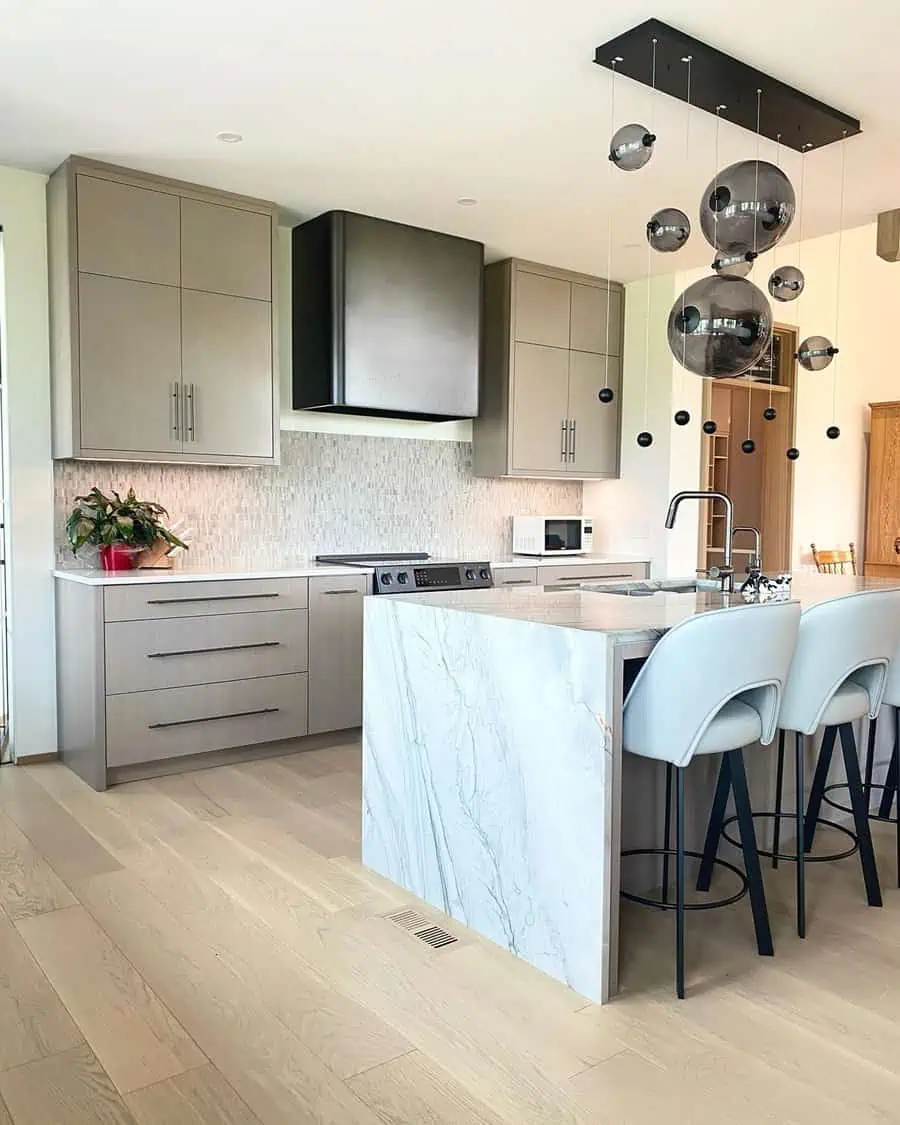 Modern minimalist open kitchen with sleek cabinetry, a marble waterfall island, and statement lighting.