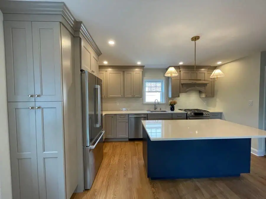 Modern minimalist open kitchen with taupe cabinetry, a navy island, and elegant pendant lighting.