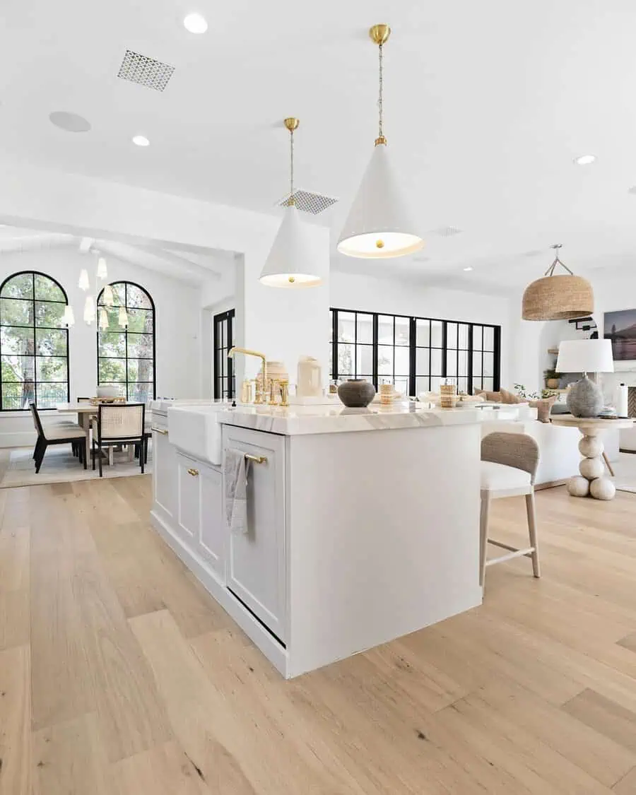 Modern minimalist open kitchen with sleek cabinetry, a marble waterfall island, and statement lighting.