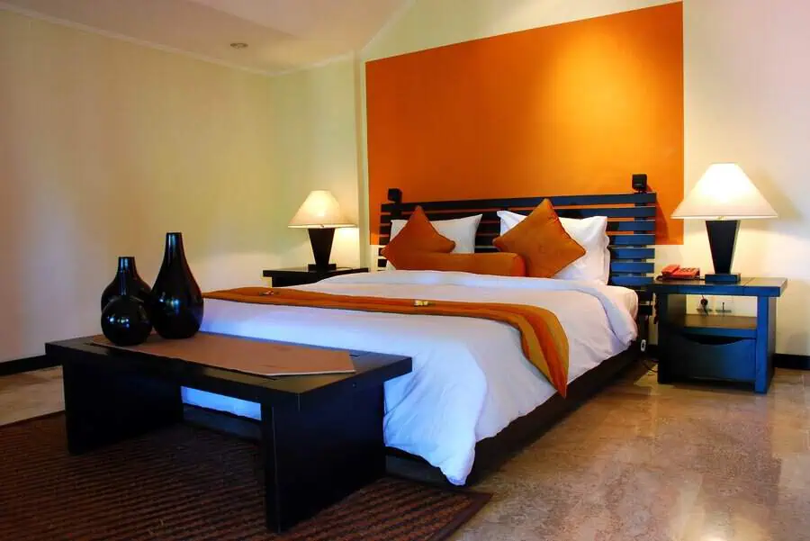 Modern orange bedroom with a bold accent wall, dark wood furniture, and elegant decor.