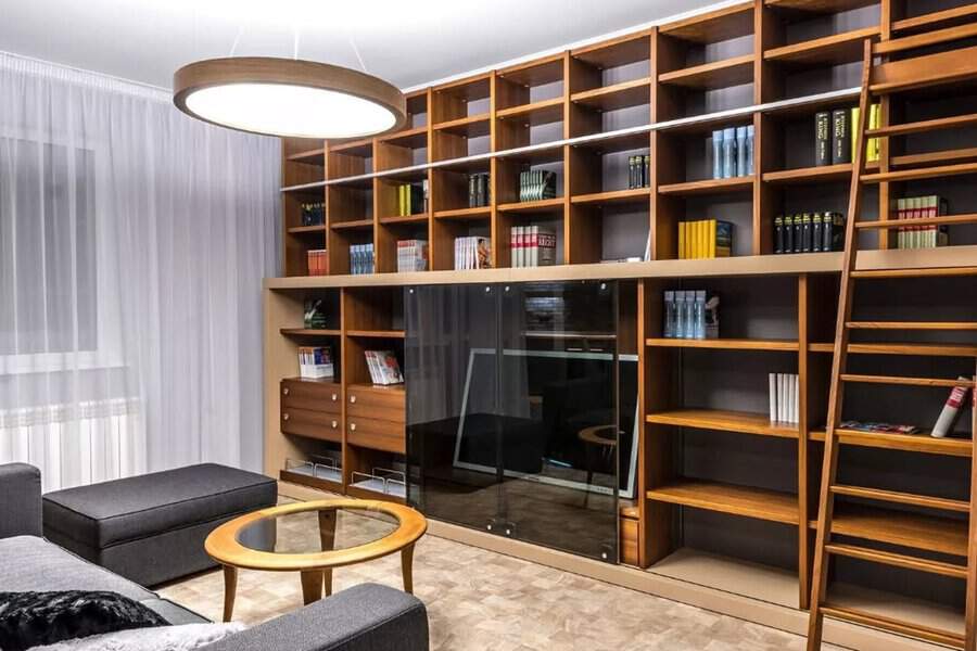 Modern living room with floor-to-ceiling modular bookshelves, a built-in TV, and a library ladder.