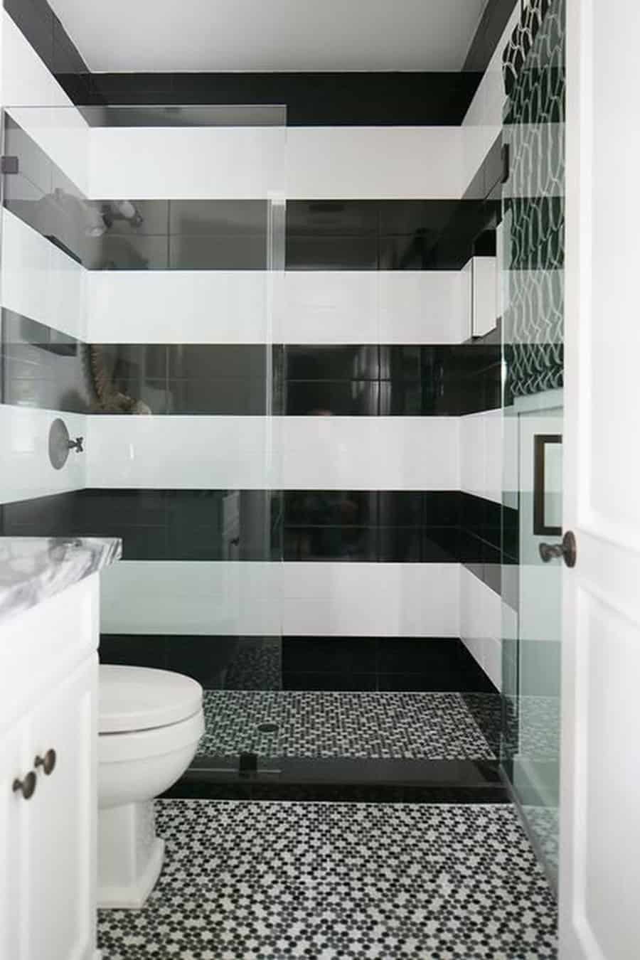 Monochrome black and white bathroom with bold striped walls and mosaic shower tiles.