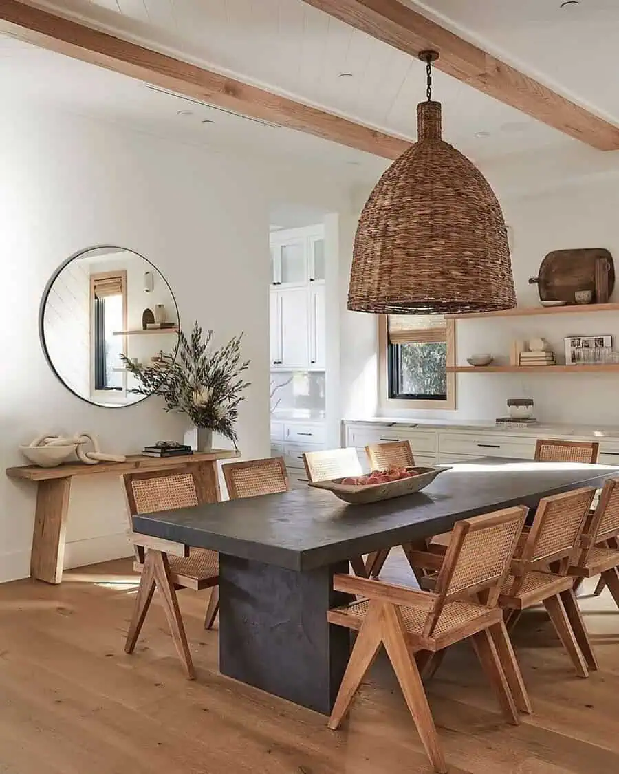 Dining room with natural light enhancing mixed wood tones, woven textures, and a stone table.