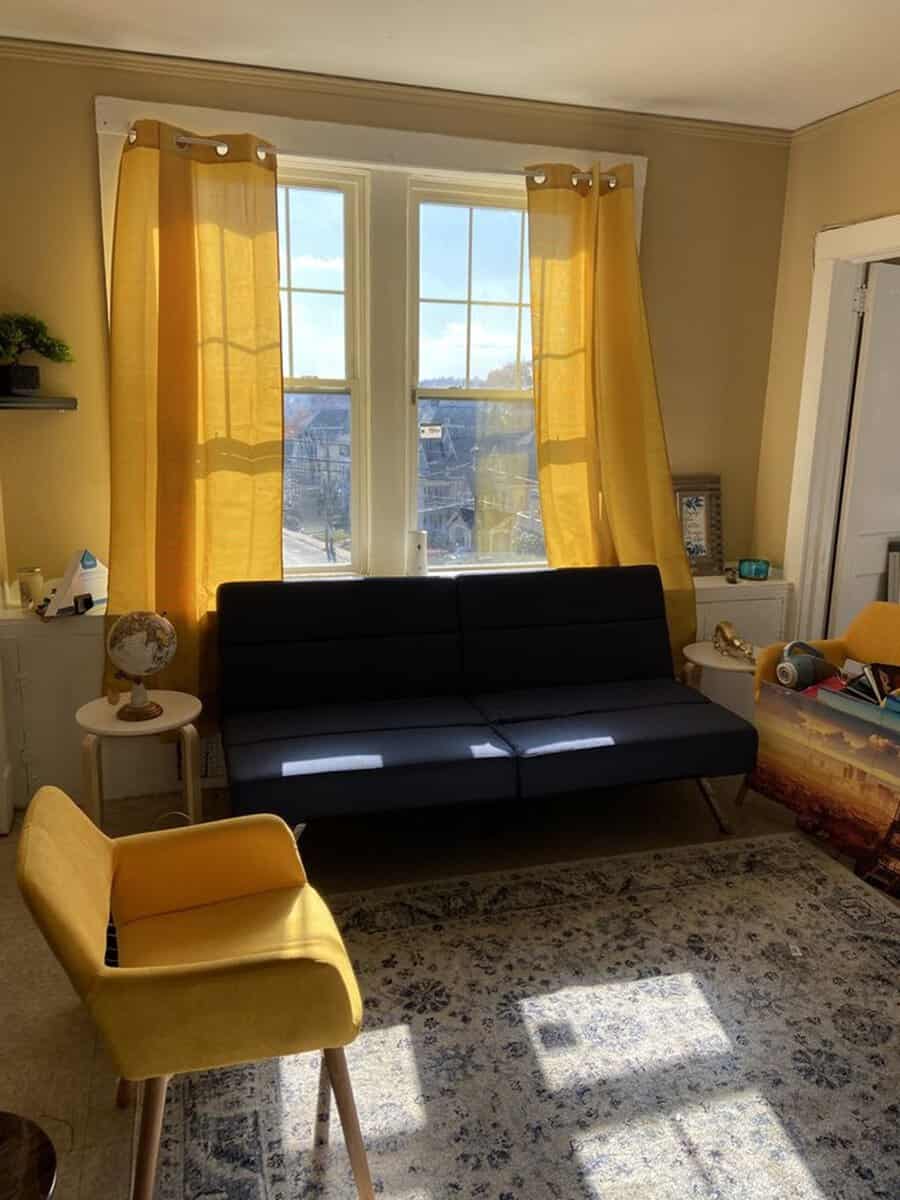 Navy blue living room with mustard yellow curtains, matching chairs, and a cozy sunlit ambiance.