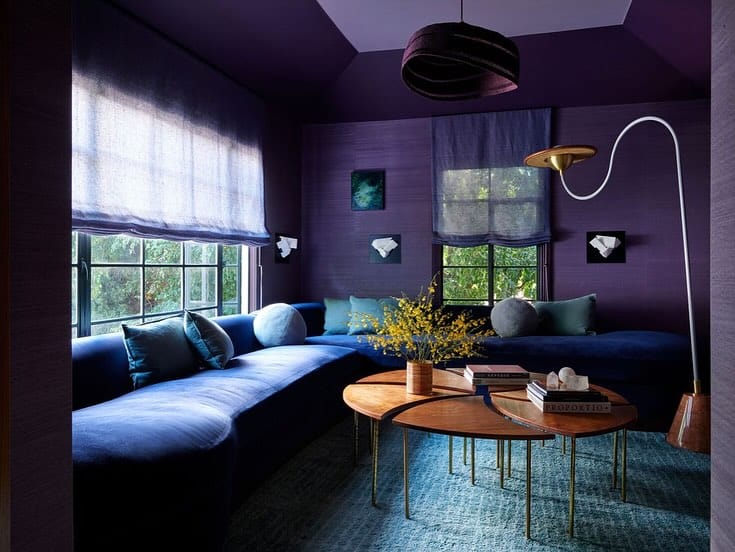 Navy blue and deep purple living room with a curved sofa, layered lighting, and modern decor.