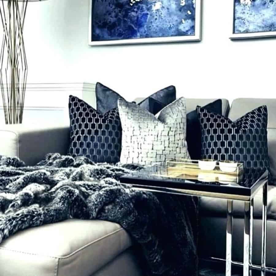 Navy blue living room with a gray sectional, plush pillows, faux fur throw, and abstract wall art.