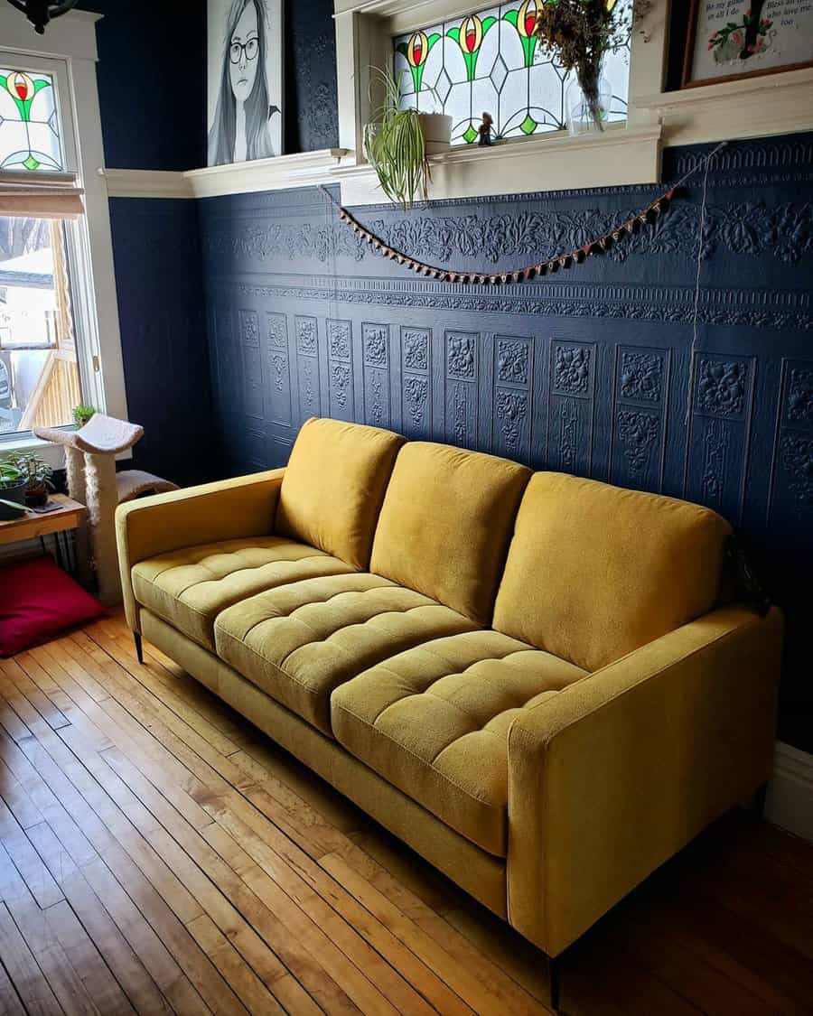 Navy blue living room with a mustard yellow sofa, textured accent wall, and stained glass windows.