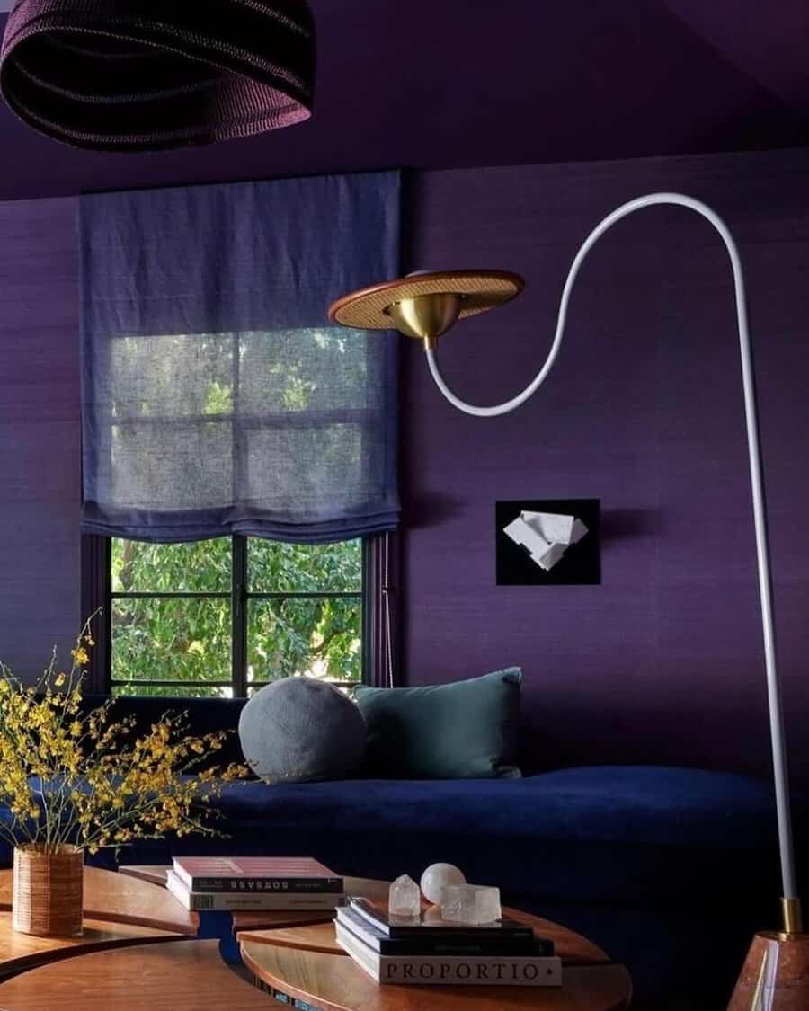 Moody navy blue and deep purple living room with soft lighting, a cozy daybed, and artistic decor.