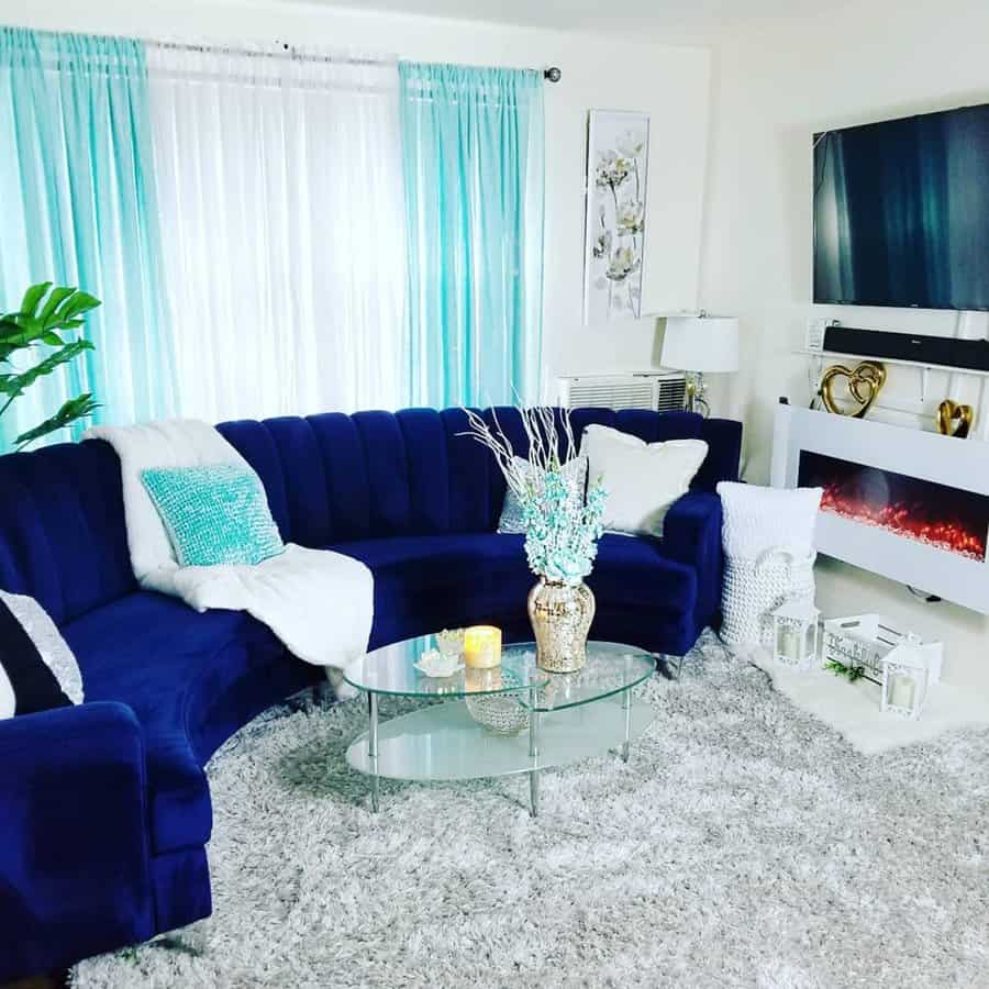 Navy blue living room with a velvet sectional, soft throws, turquoise accents, and a warm fireplace.