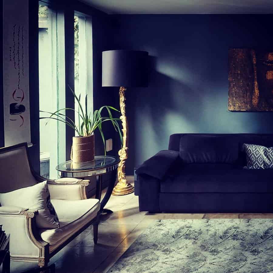 Elegant navy blue living room with a dark sofa, gold floor lamp, and a stylish accent chair.