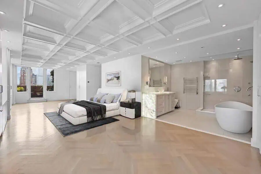 Luxury open-concept bedroom with a modern coffered ceiling, sleek ensuite bathroom, and city views.