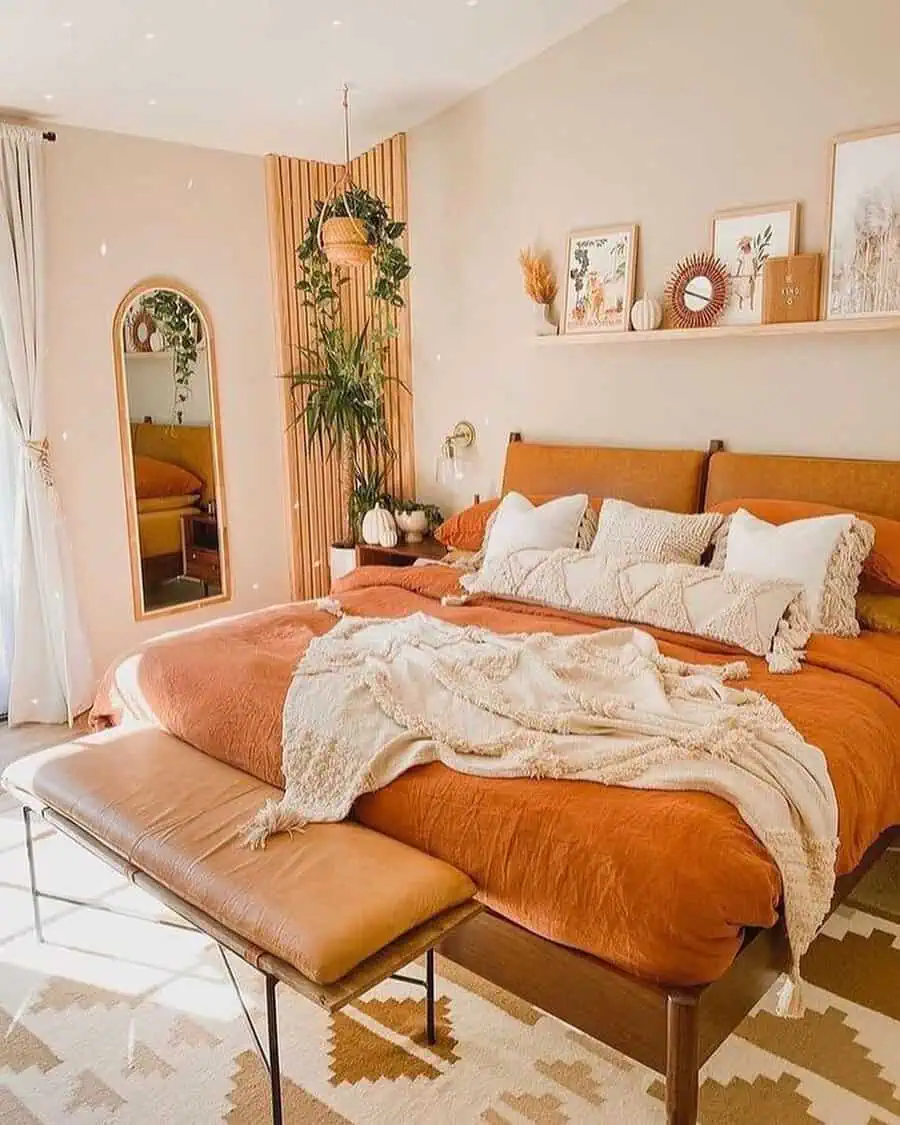 Orange bedroom with a leather headboard, stylish bench, wooden accents, and boho decor.