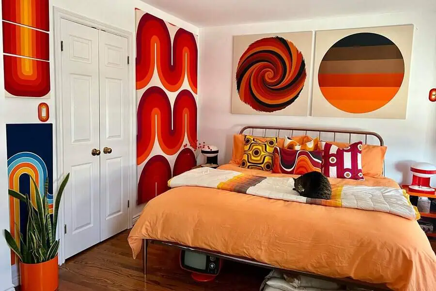 Orange bedroom with bold artistic wall murals, retro geometric patterns, and vibrant decor accents.