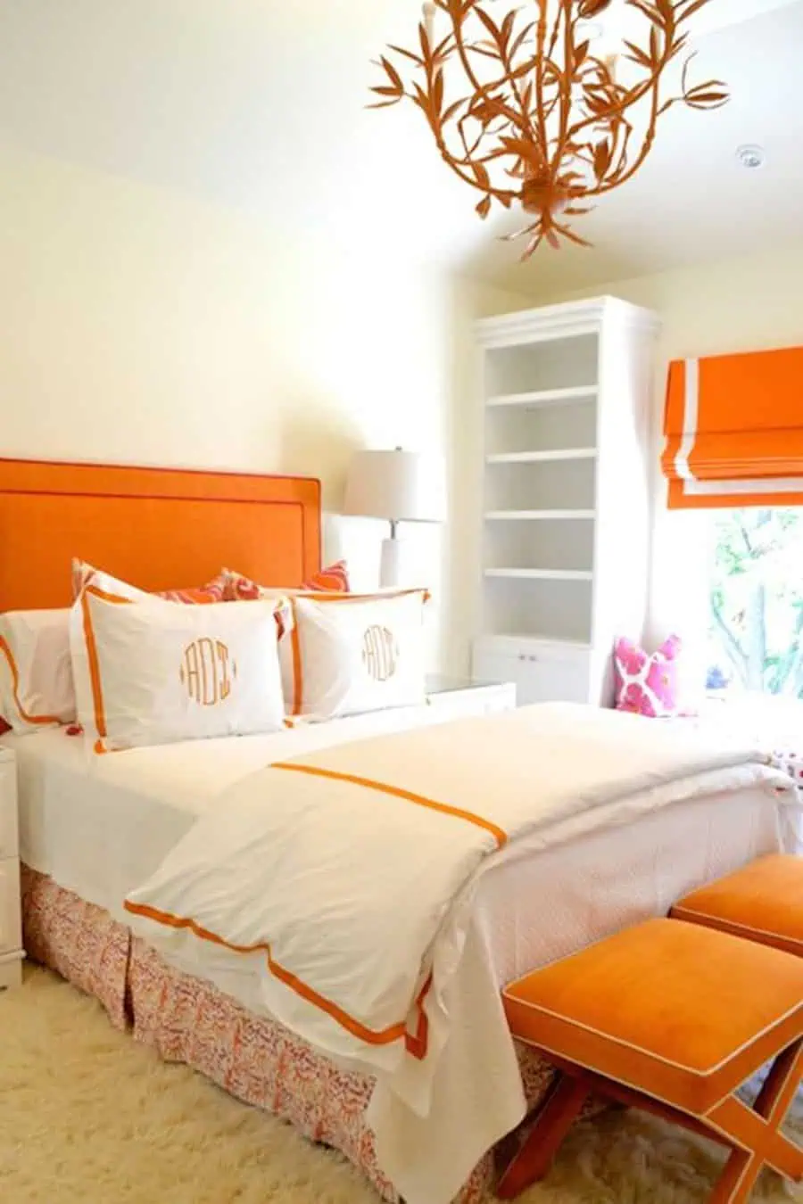 Orange bedroom with a bold upholstered headboard, crisp white bedding, and elegant accent decor.