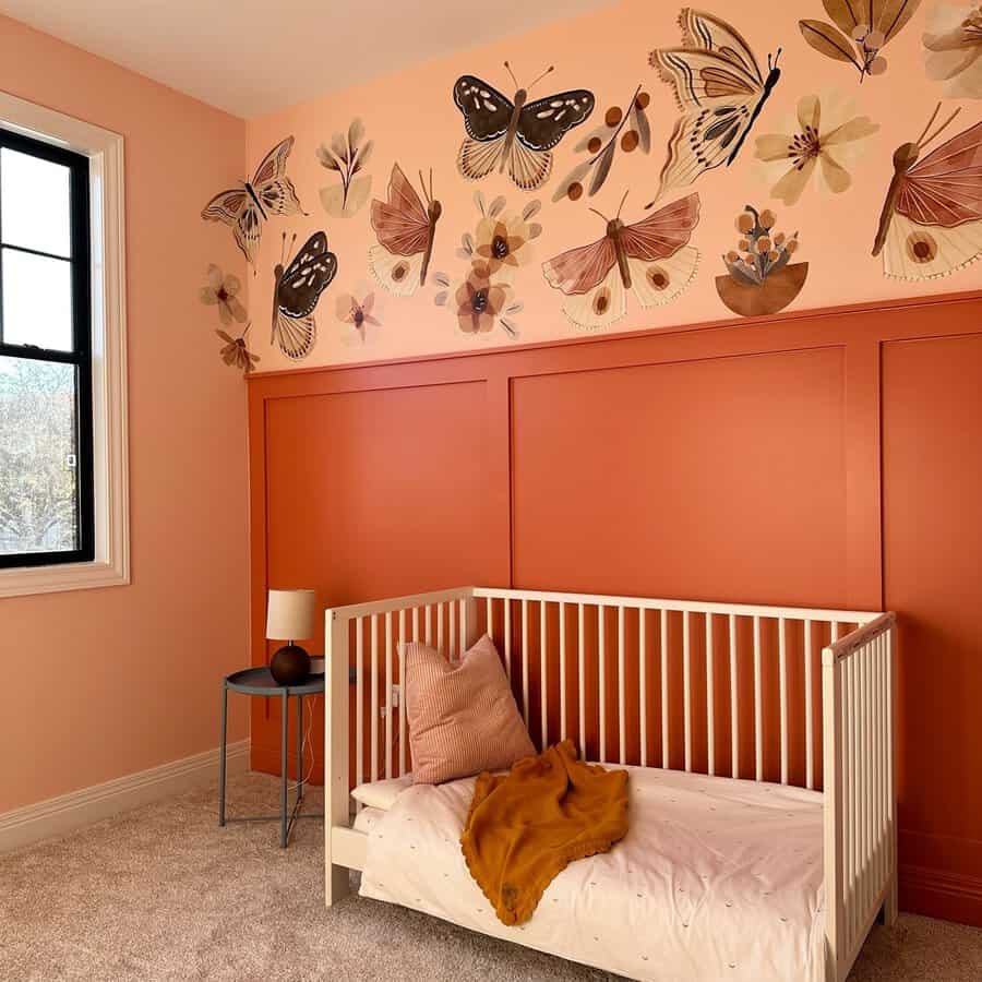 Pastel orange nursery with soft tones, butterfly wall art, cozy textures, and a minimalist aesthetic.