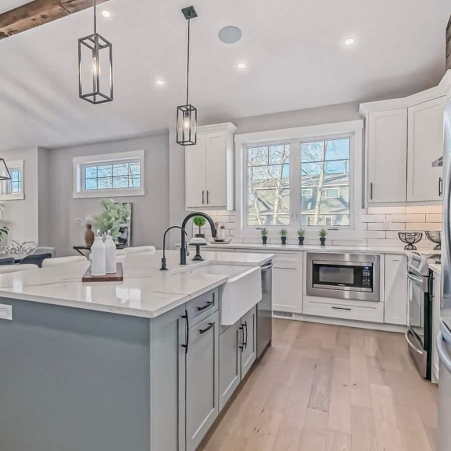 Modern farmhouse kitchen with white cabinets, a large island, and black pendant lighting.