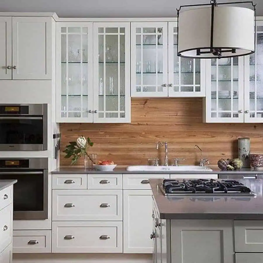 Rustic wood backsplash adds warmth and texture to white cabinets, creating a cozy and inviting kitchen.