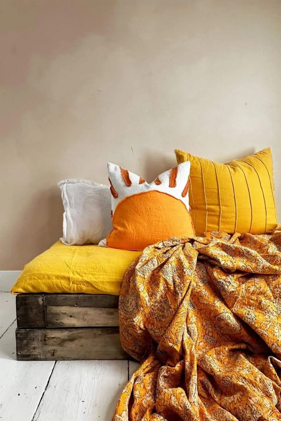 Rustic wooden bed frame with plush orange and mustard cushions, creating a warm and cozy bedroom.