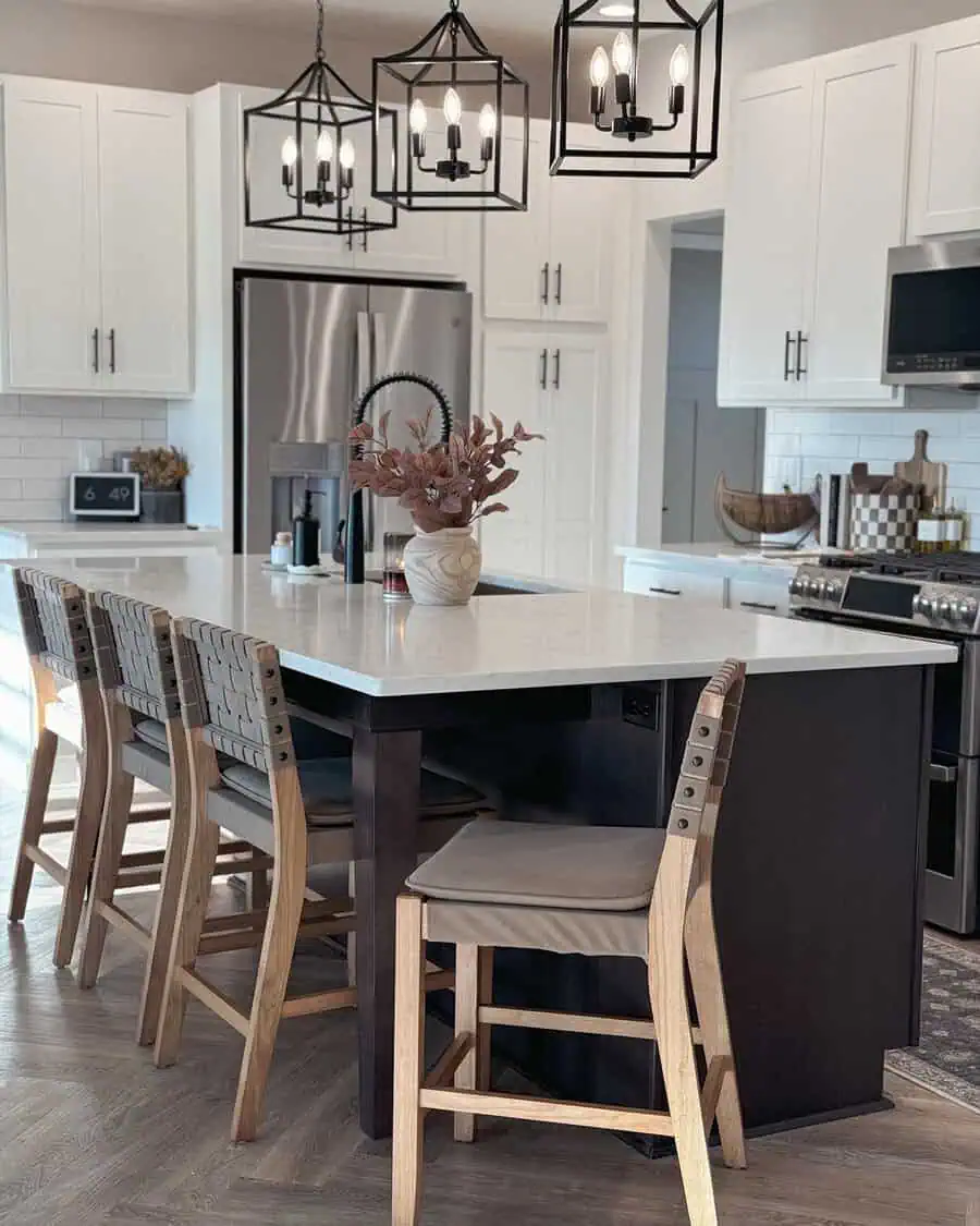 Simple kitchen with bold pendant lighting, white cabinetry, a dark island, and woven bar stools.