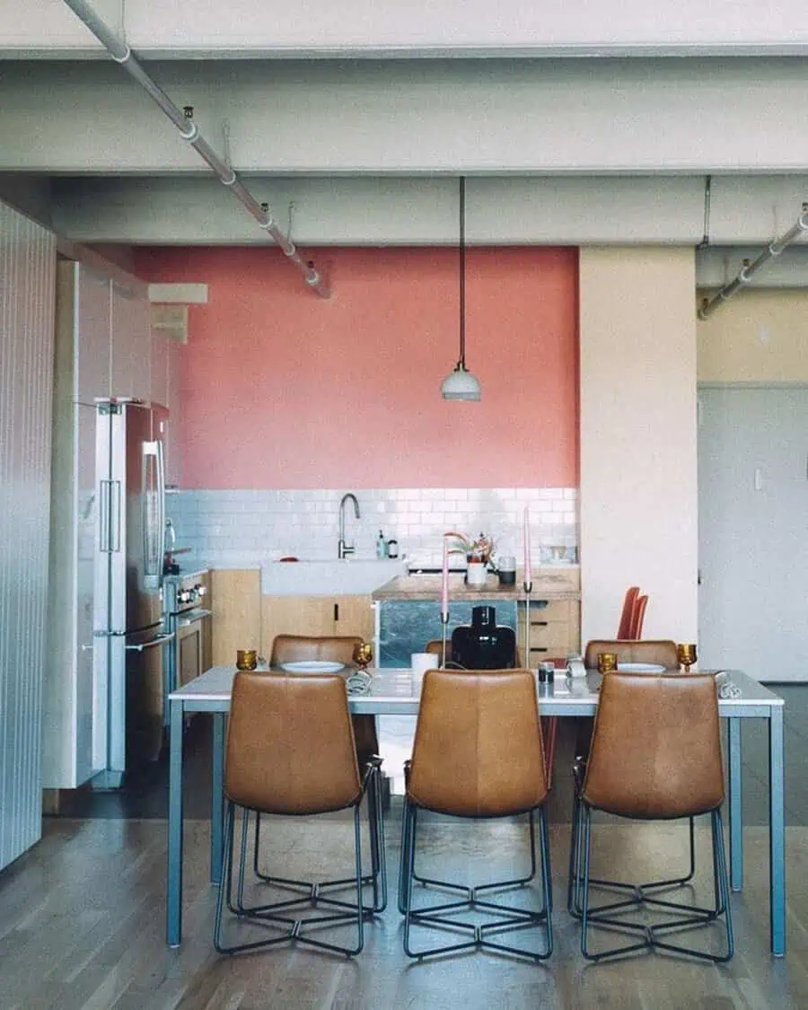 Simple kitchen design with a bold pink accent wall, white subway tile backsplash, and warm wood cabinetry.