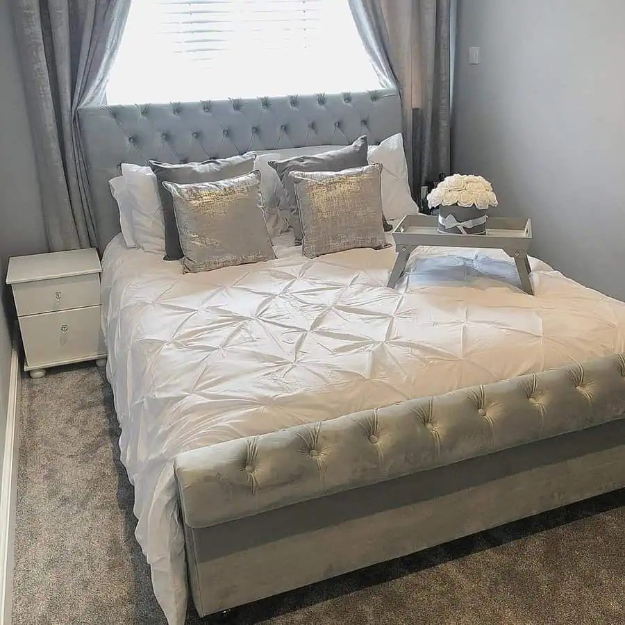 Simple modern grey and white bedroom with a tufted bed, plush pillows, and elegant decor.