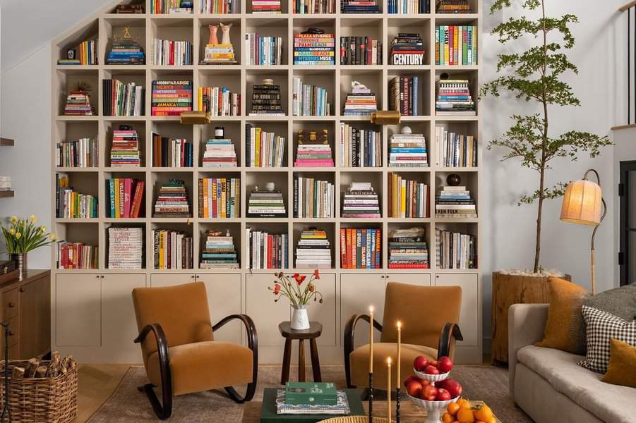 Sitting area home library with floor-to-ceiling bookshelves, cozy chairs, and warm decor.
