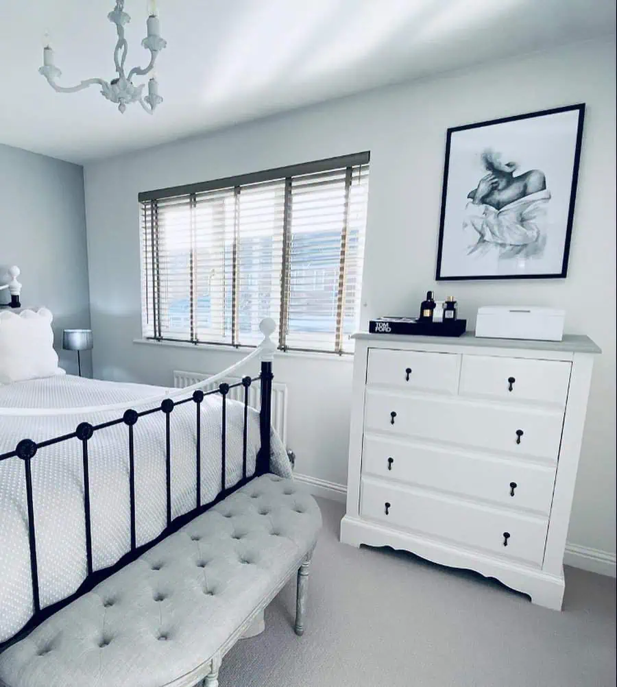 Sleek modern grey and white bedroom with a metal bed frame, tufted bench, and elegant decor.